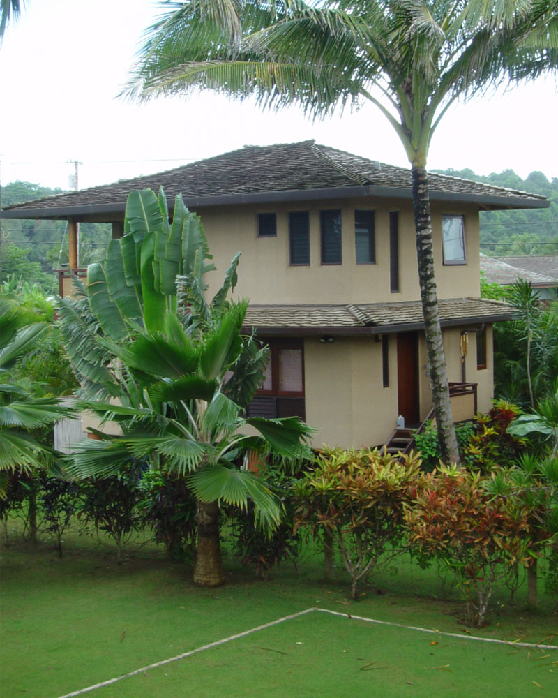 Lush tropical vegetation surrounds the house.